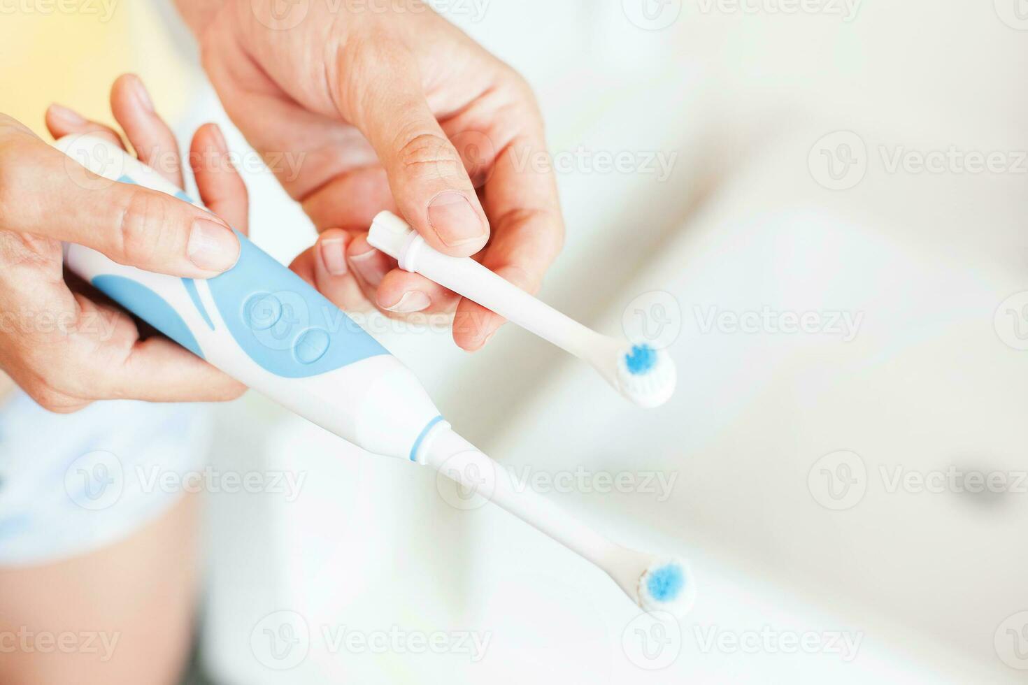 a person holding two toothbrushes in front of a sink photo