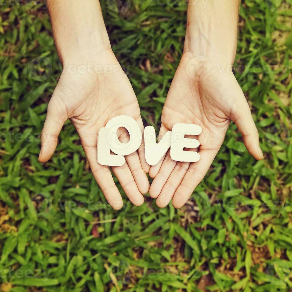 woman holding love word in her hands on grass background photo