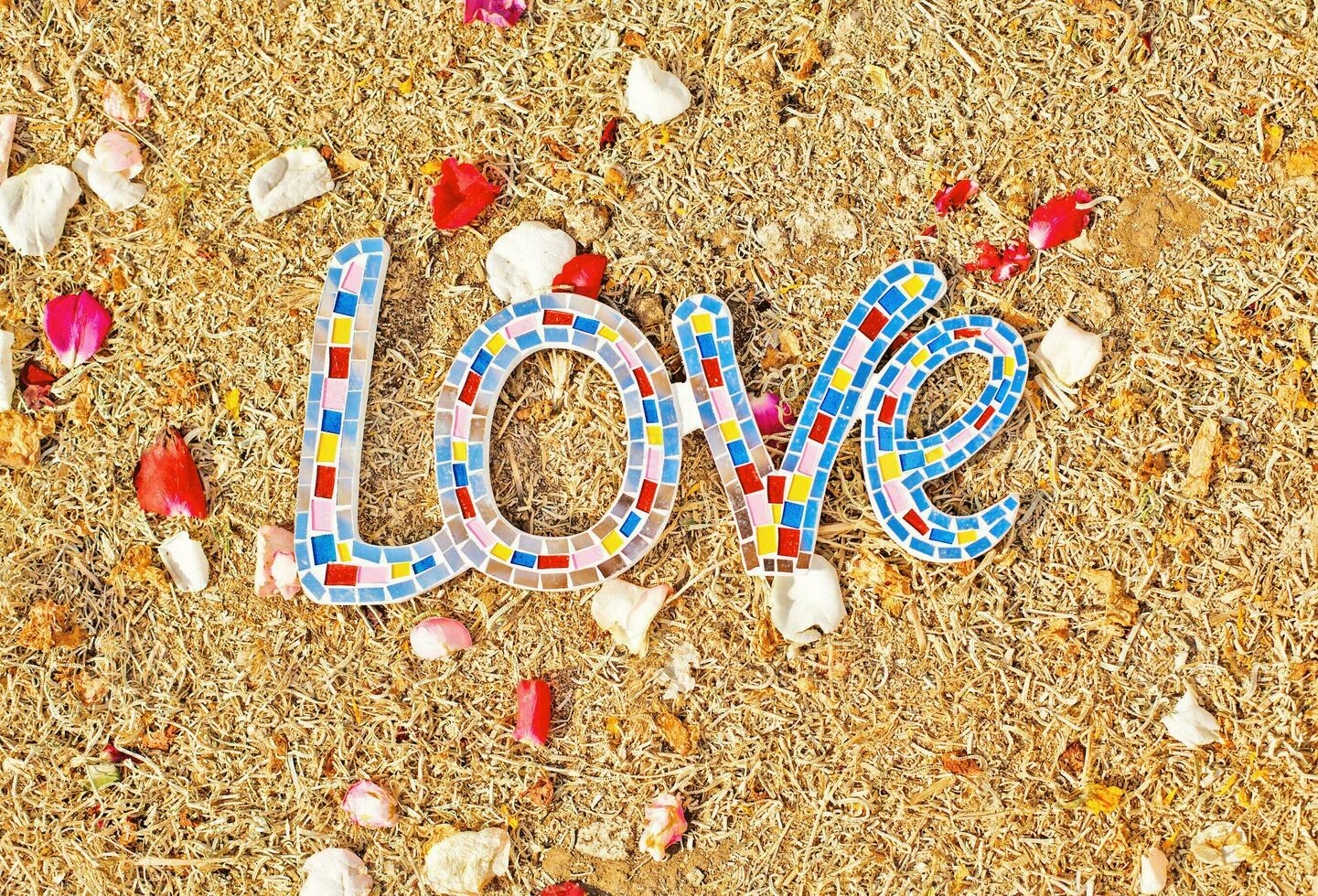 amor palabra hecho de vistoso mosaico losas en el playa foto