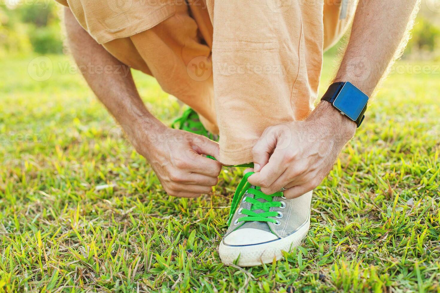 a man tying his shoes on a grassy field photo