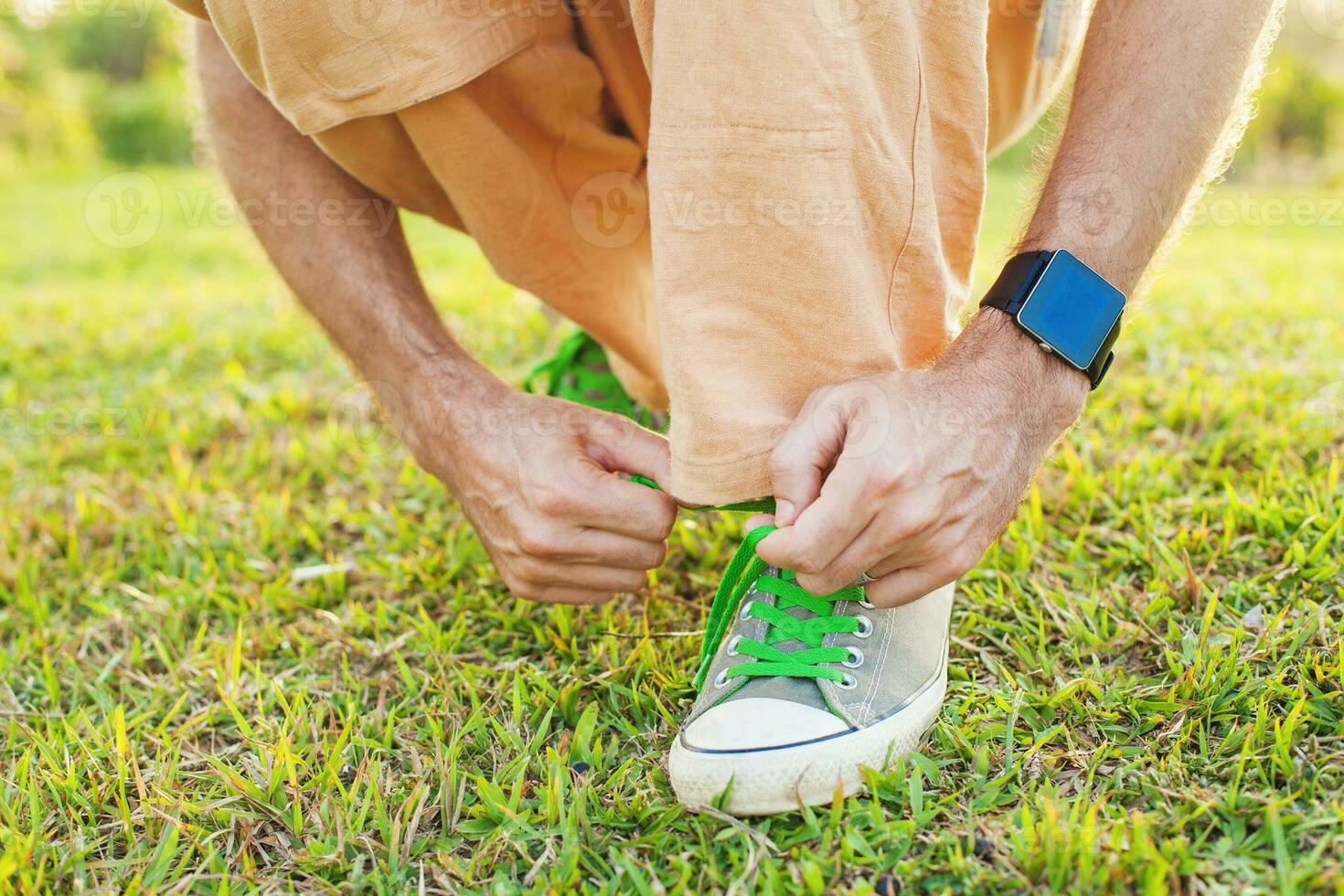 un hombre atadura su Zapatos en un herboso campo foto