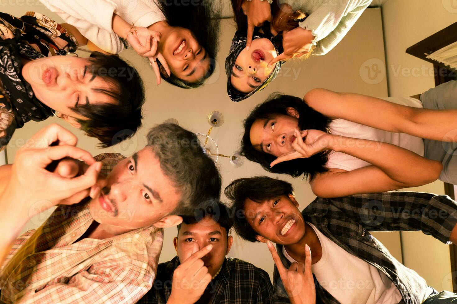 a group of Asian teenagers forming a circle and looking down with funny faces in an old room photo