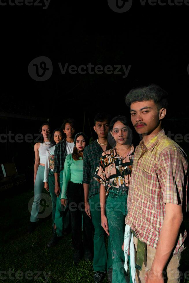 un grupo de asiático personas en pie y recubrimiento arriba mirando a el cámara foto