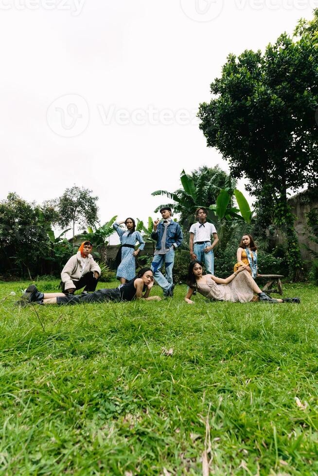 a group of asian people having a picnic in a park with green grass photo