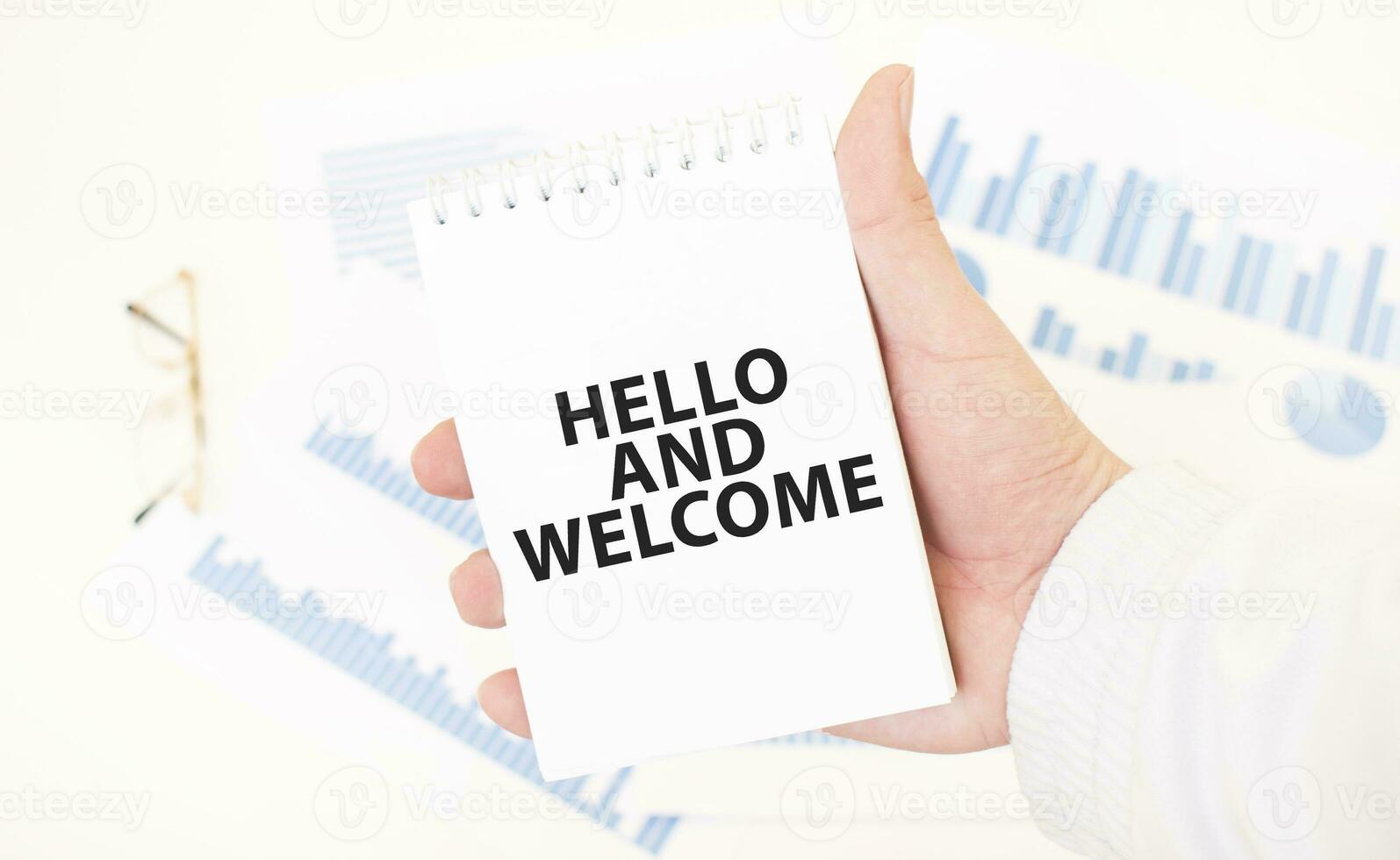 Businessman holding a white notepad with text HELLO AND WELCOME, business concept photo