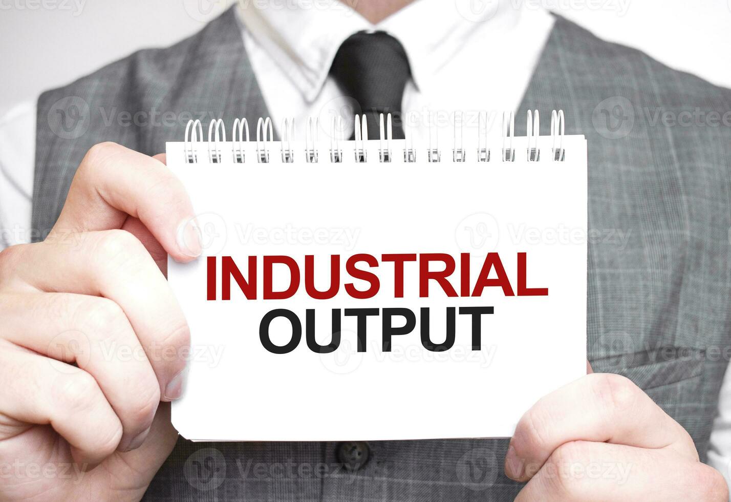 Businessman with notebook with text INDUSTRIAL OUTPUT photo
