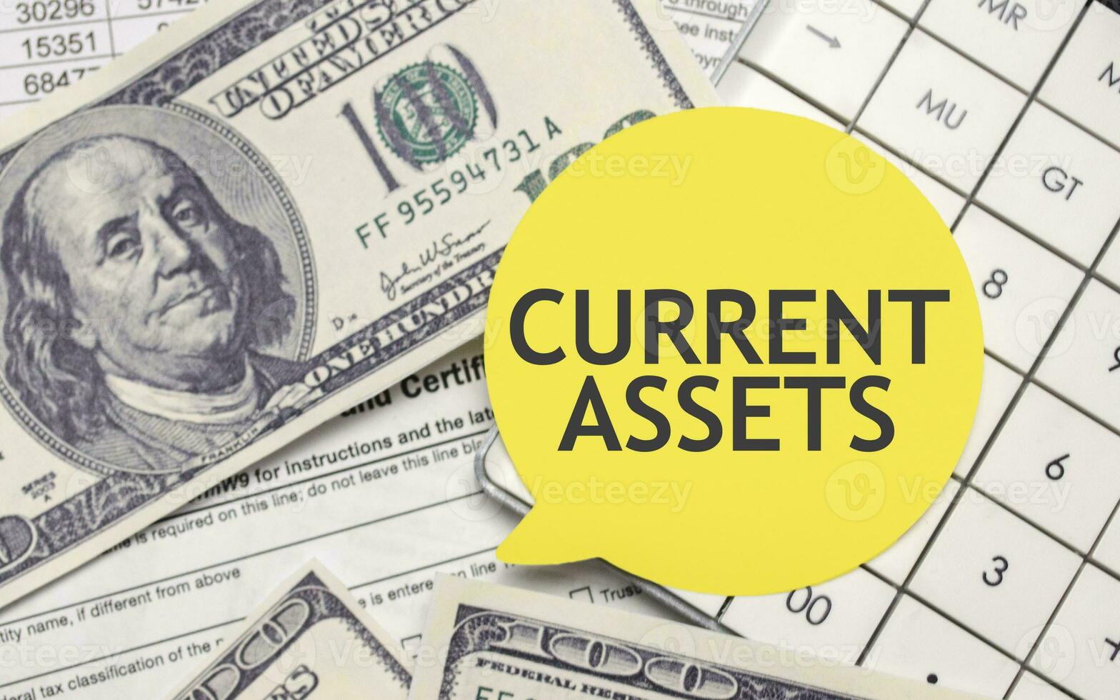 CURRENT ASSETS words on yellow sticker with dollars and charts photo