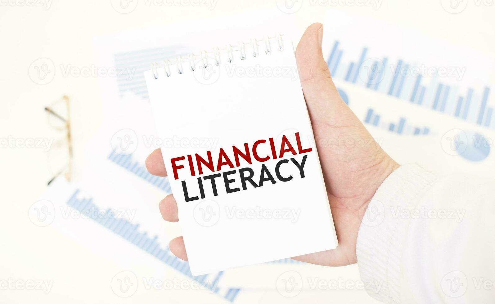 Businessman holding a white notepad with text FINANCIAL LITERACY, business concept photo