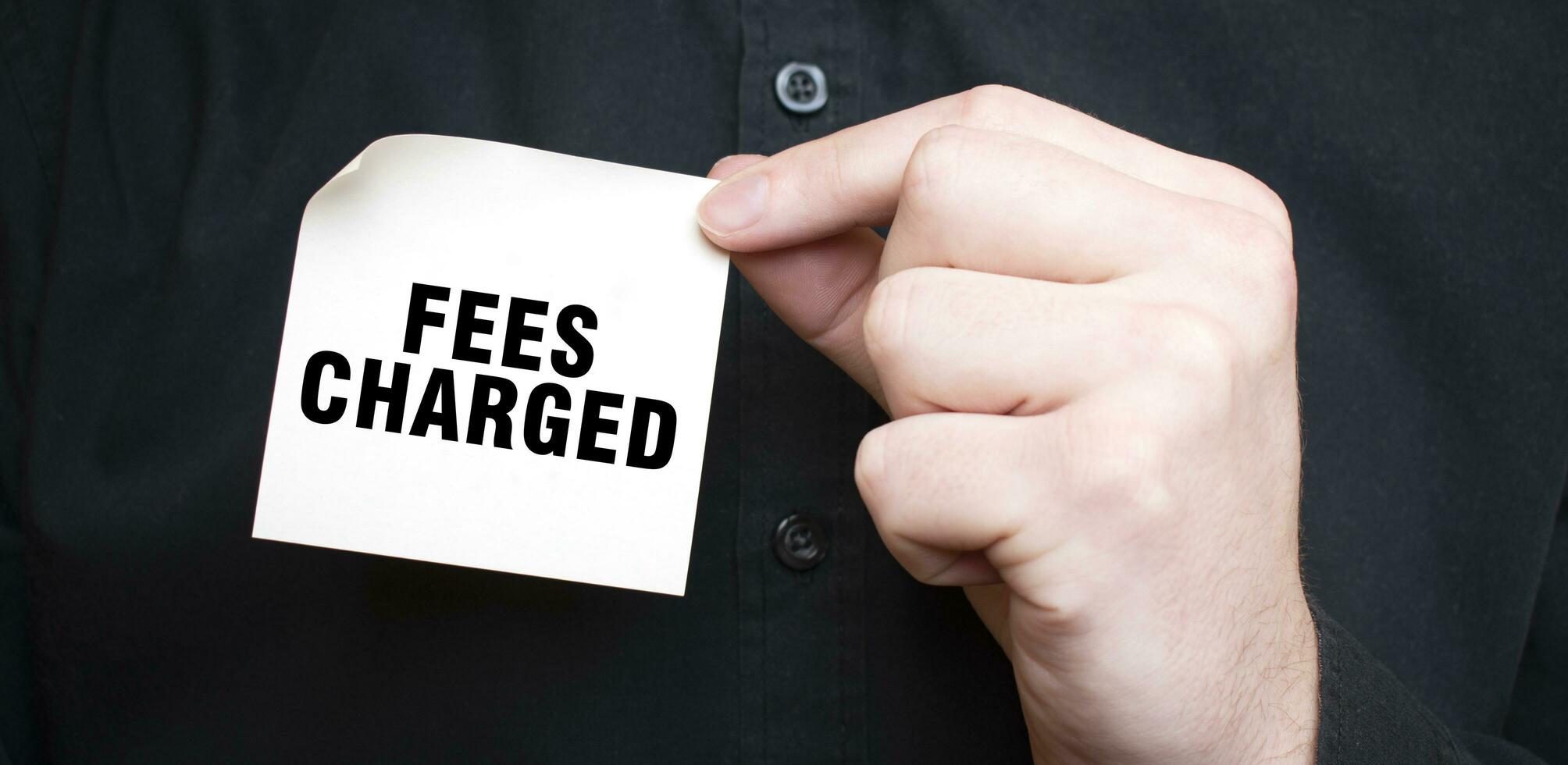 Businessman holding a card with text FEES CHARGED, business concept photo