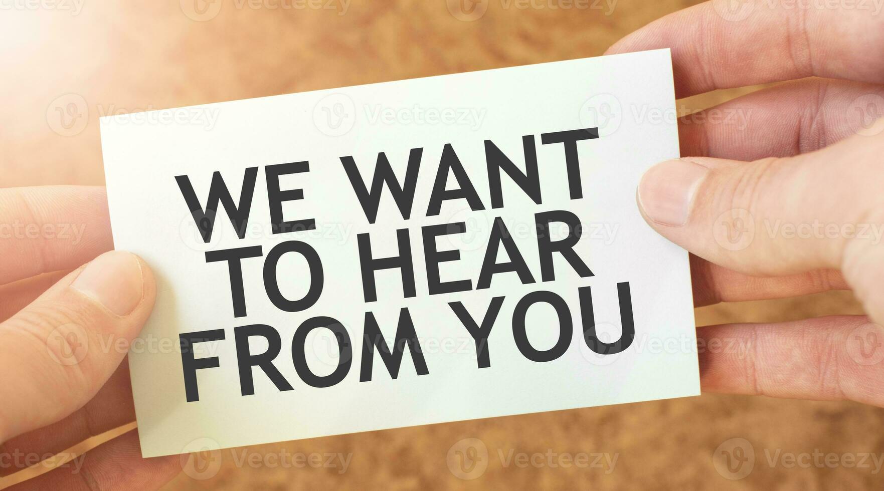 WE WANT TO HEAR FROM YOU word inscription on white card paper sheet in hands of a businessman. recap concept. red and white paper photo