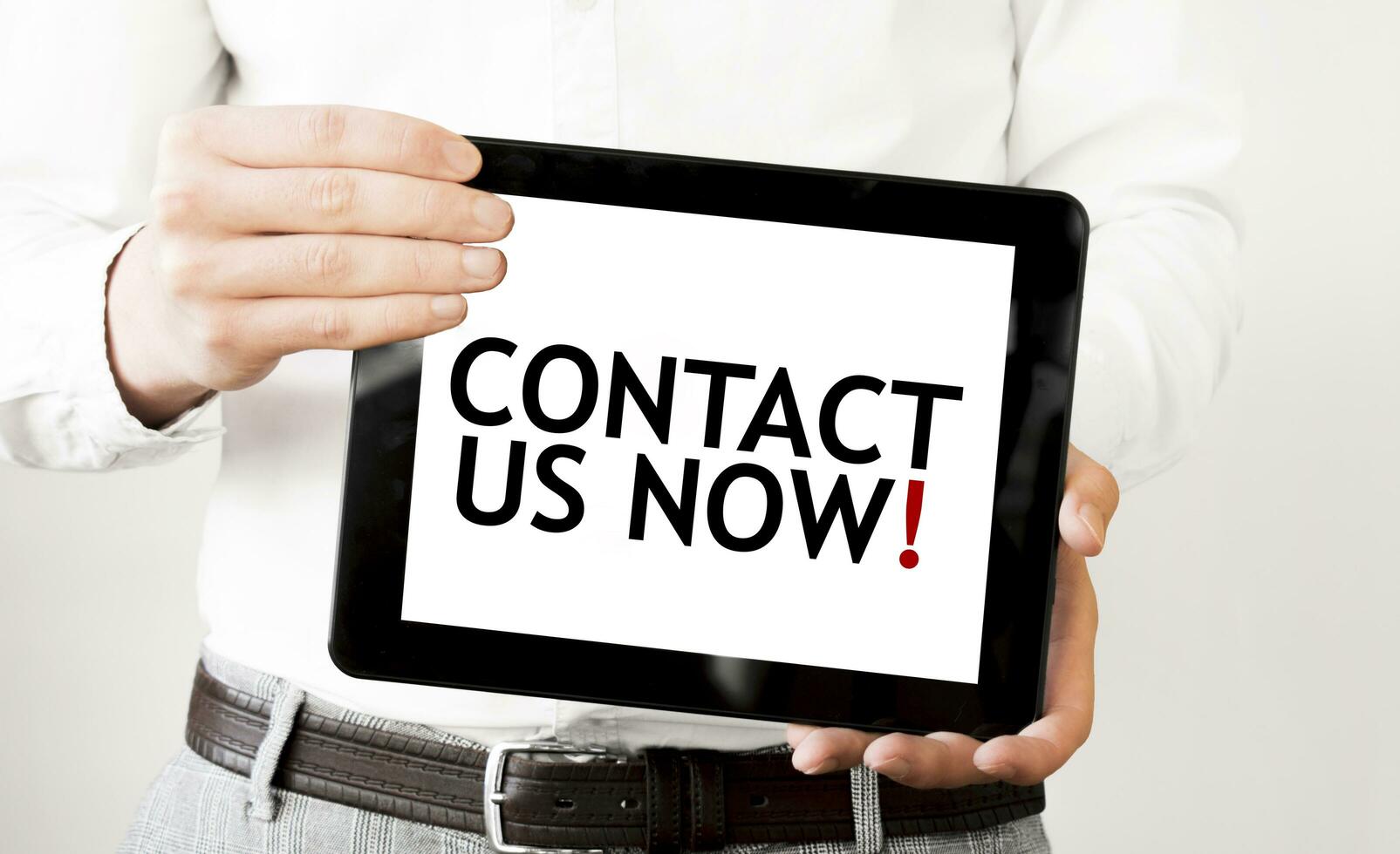 Text CONTACT US NOW on tablet display in businessman hands on the white background. Business concept photo