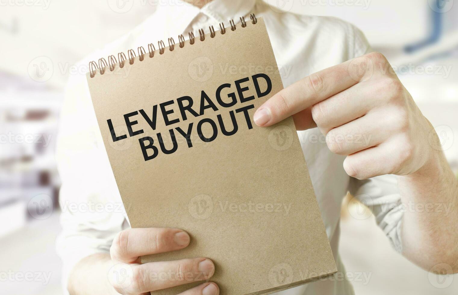 Text LEVERAGED BUYOUTon brown paper notepad in businessman hands in office. Business concept photo