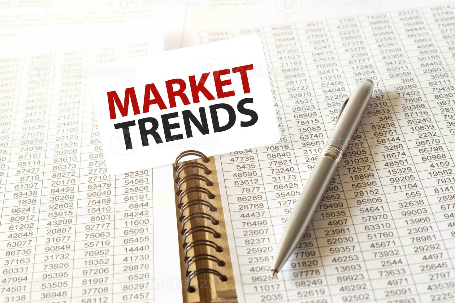 Text MARKET TRENDS on paper card, pen, financial documentation on table photo