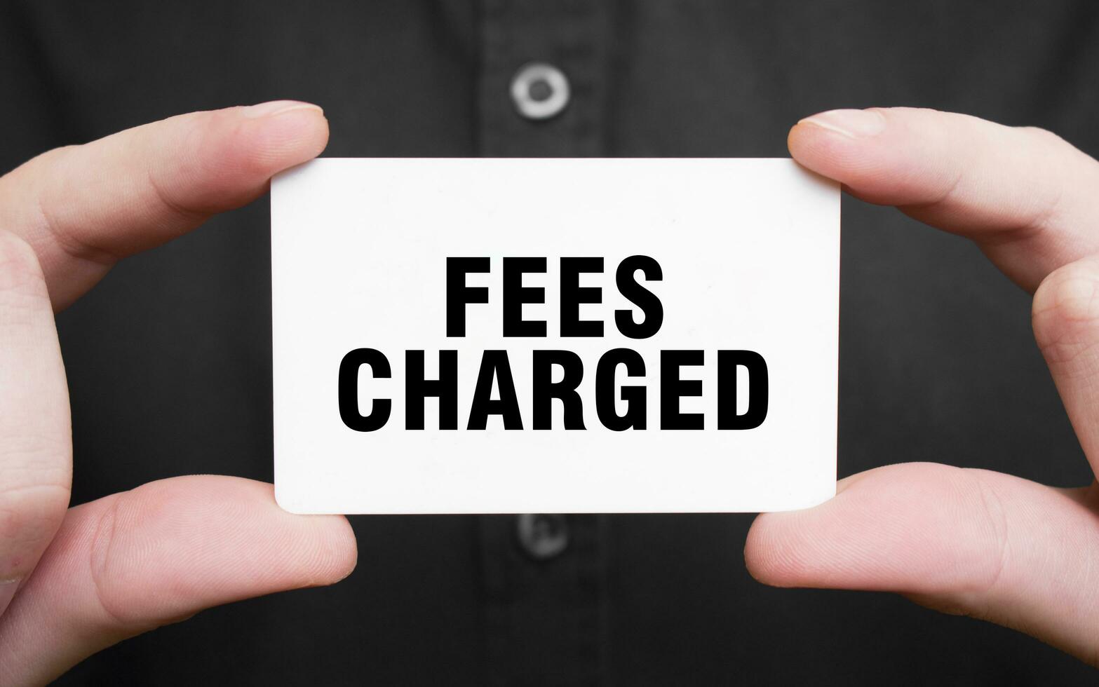 Businessman holding a card with text FEES CHARGED, business concept photo