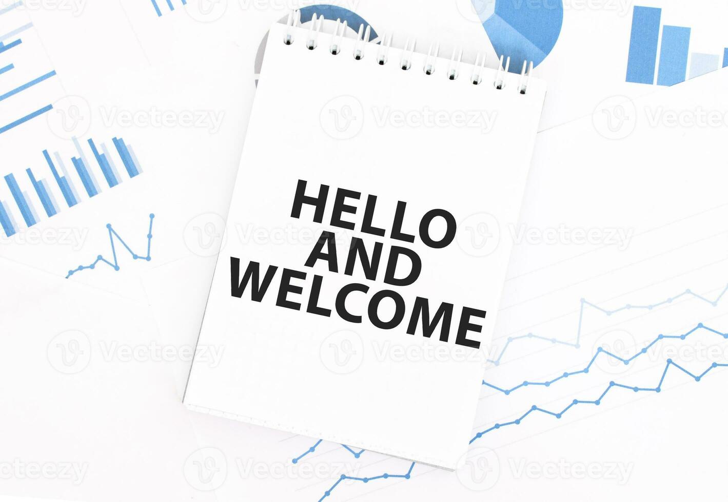 White notepad with text HELLO AND WELCOME on the financial documentation. Finance and business concept photo