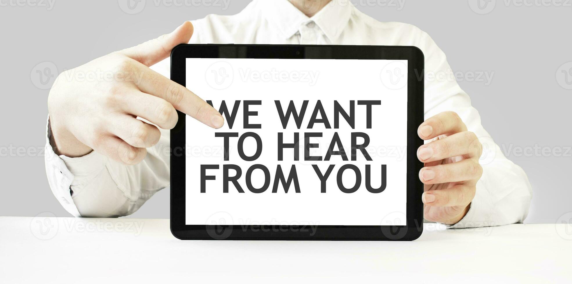 Text WE WANT TO HEAR FROM YOU on tablet display in businessman hands on the white background. Business concept photo
