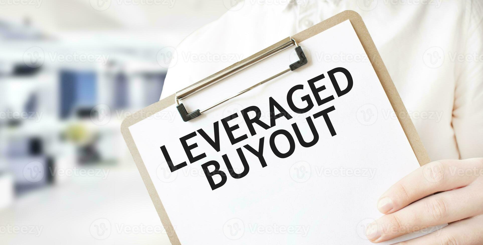 Text LEVERAGED BUYOUT on white paper plate in businessman hands in office. Business concept photo