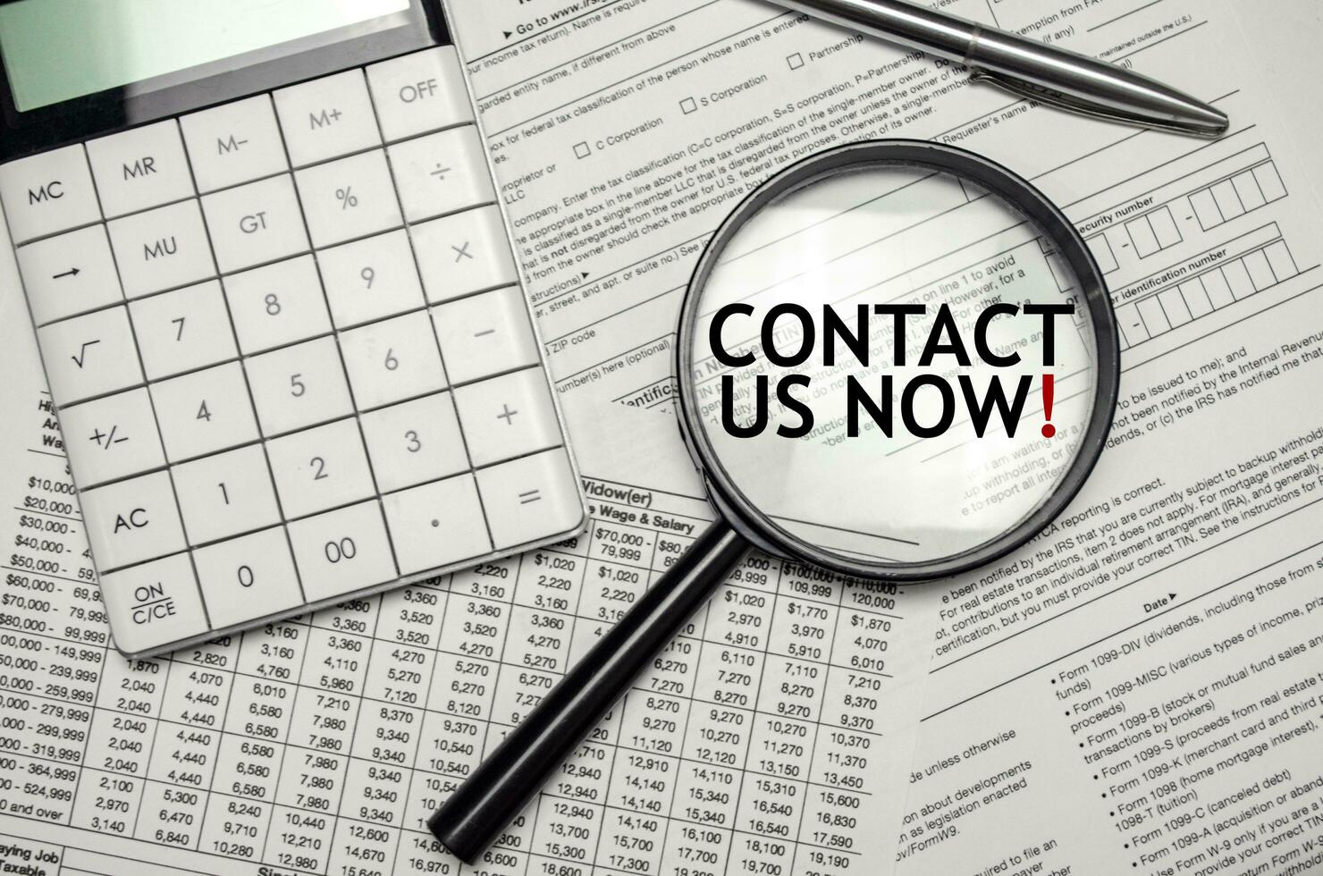 CONTACT US NOW words on magnifier glass and calculator with pen photo