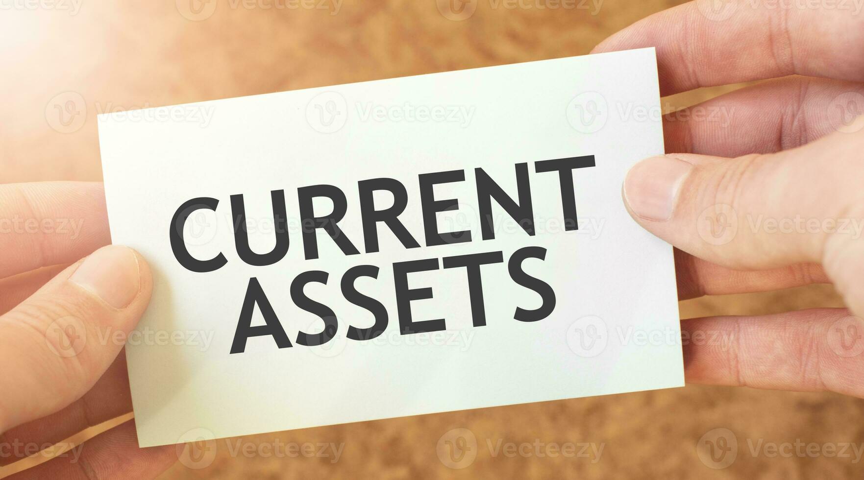 CURRENT ASSETS word inscription on white card paper sheet in hands of a businessman. recap concept. red and white paper photo