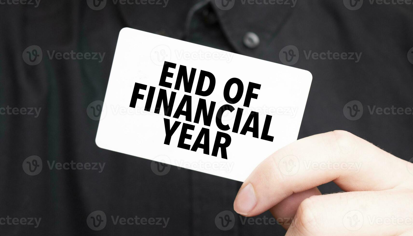 Businessman holding a card with text END OF FINANCIAL YEAR, business concept photo