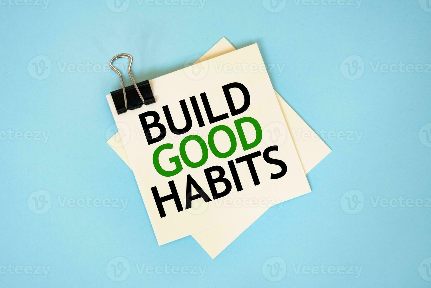 Text BUILD GOOD HABITS on sticky notes with copy space and paper clip isolated on red background.Finance and economics concept. photo