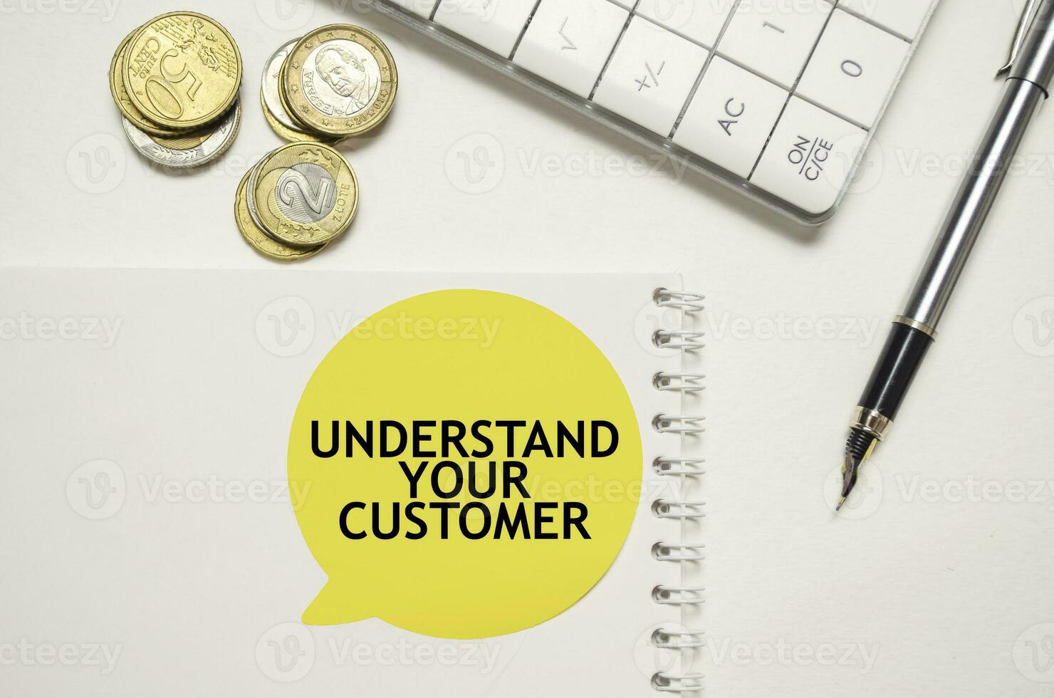 UNDERSTAND YOUR CUSTOMER words on yellow sticker with dollars with calculator and pen photo