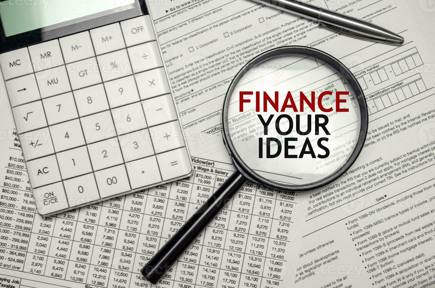 FINANCE YOUR IDEAS words on magnifier glass and calculator with pen photo