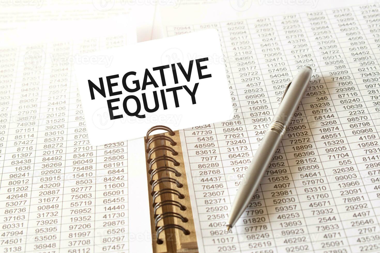 Text NEGATIVE EQUITY on paper card, pen, financial documentation on table photo