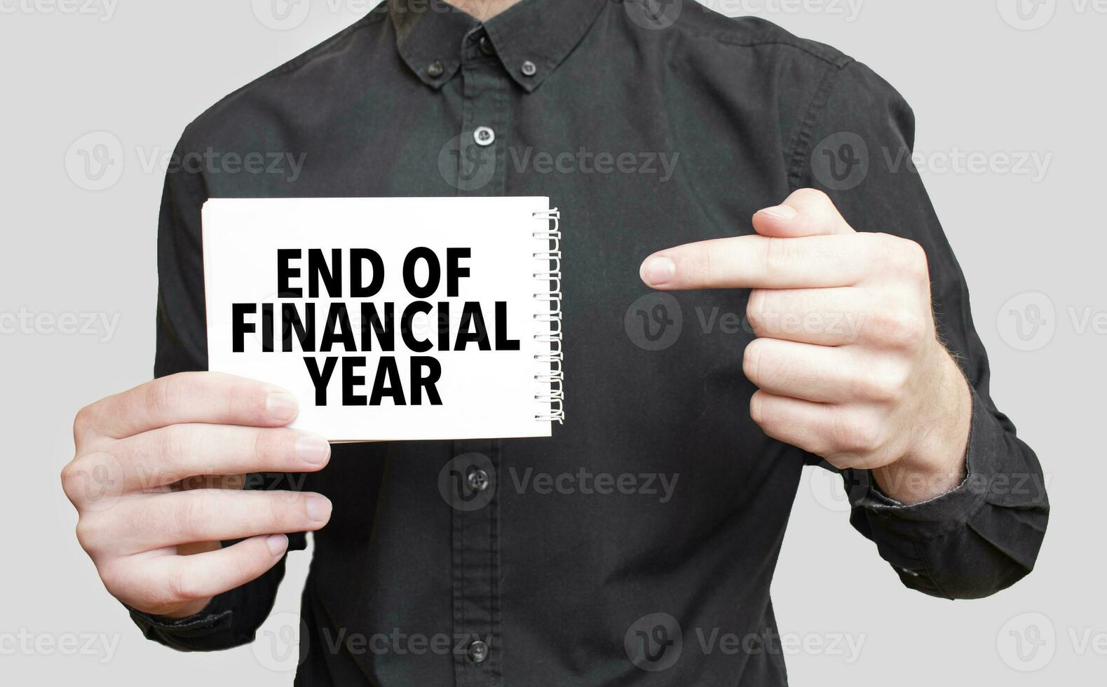 Businessman holding a white notepad with text END OF FINANCIAL YEAR, business concept photo