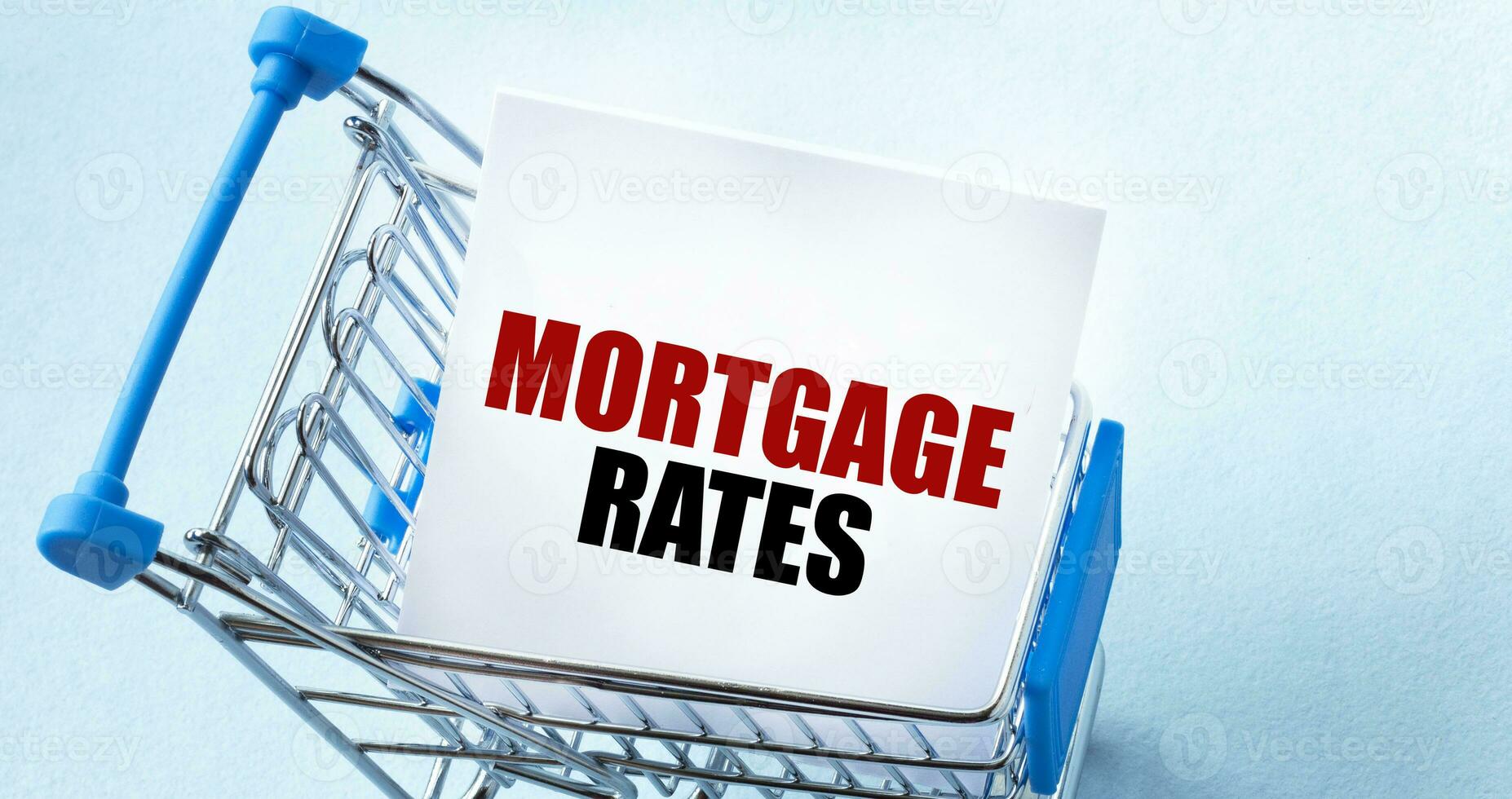 Shopping cart and text MORTGAGE RATES on white paper note list. Shopping list concept on blue background. photo