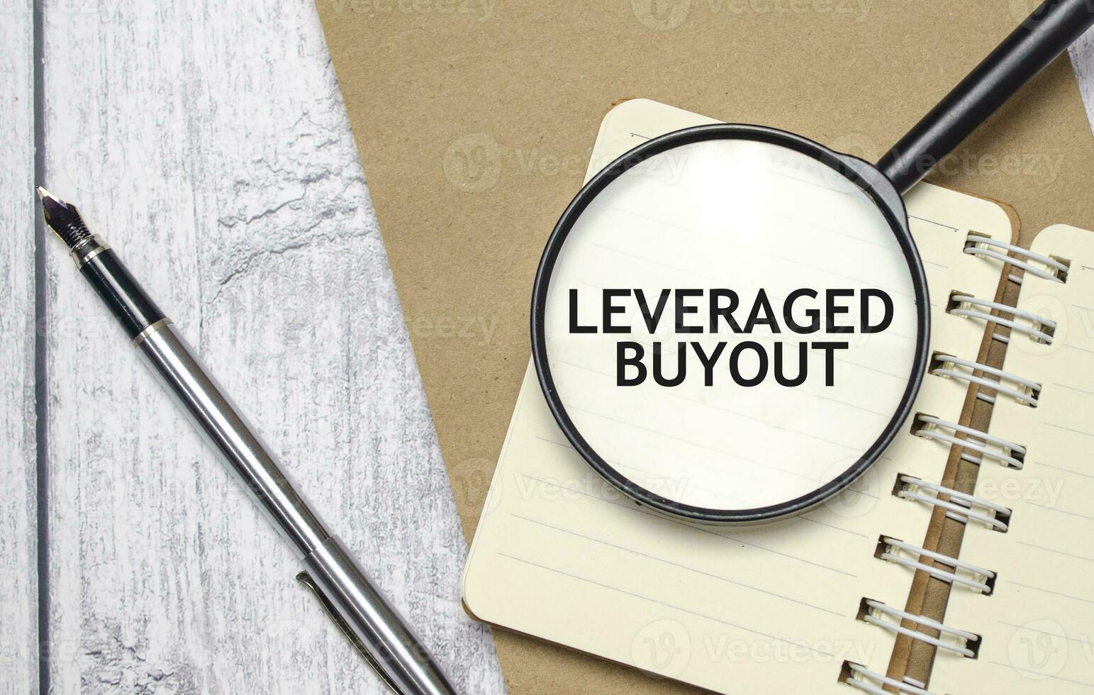 LEVERAGED BUYOUT words on magnifier glass with notebook and pen photo