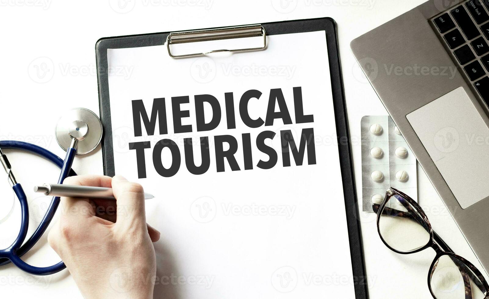 Doctor holding a pen and card with text medical tourism, medical concept photo