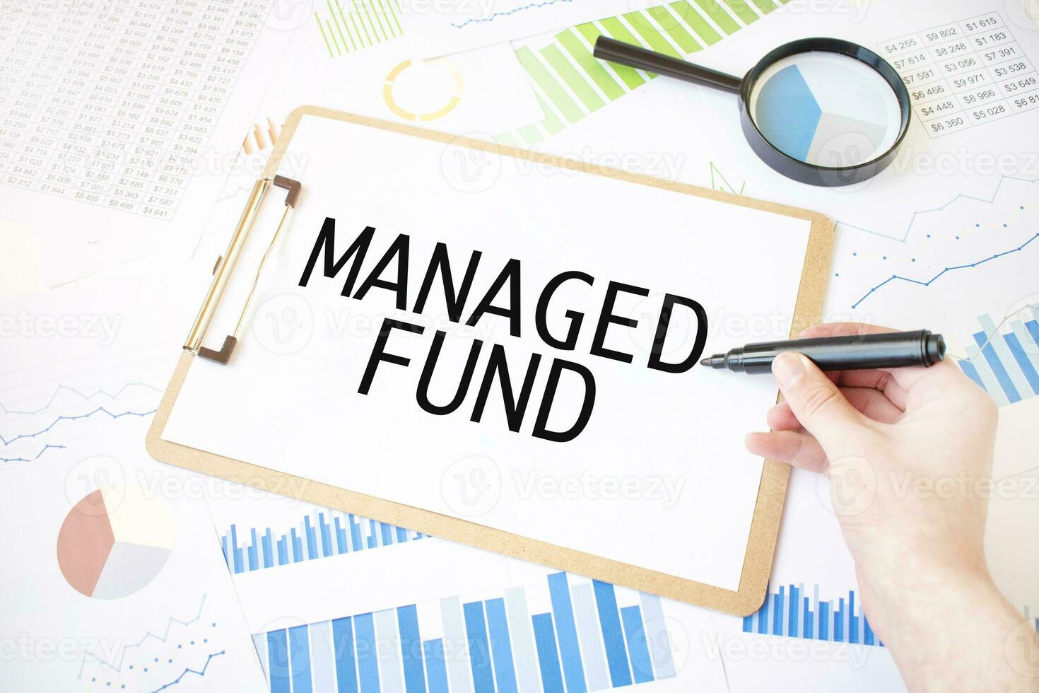 Text MANAGED FUND on white paper sheet and marker on businessman hand on the diagram. Business concept photo