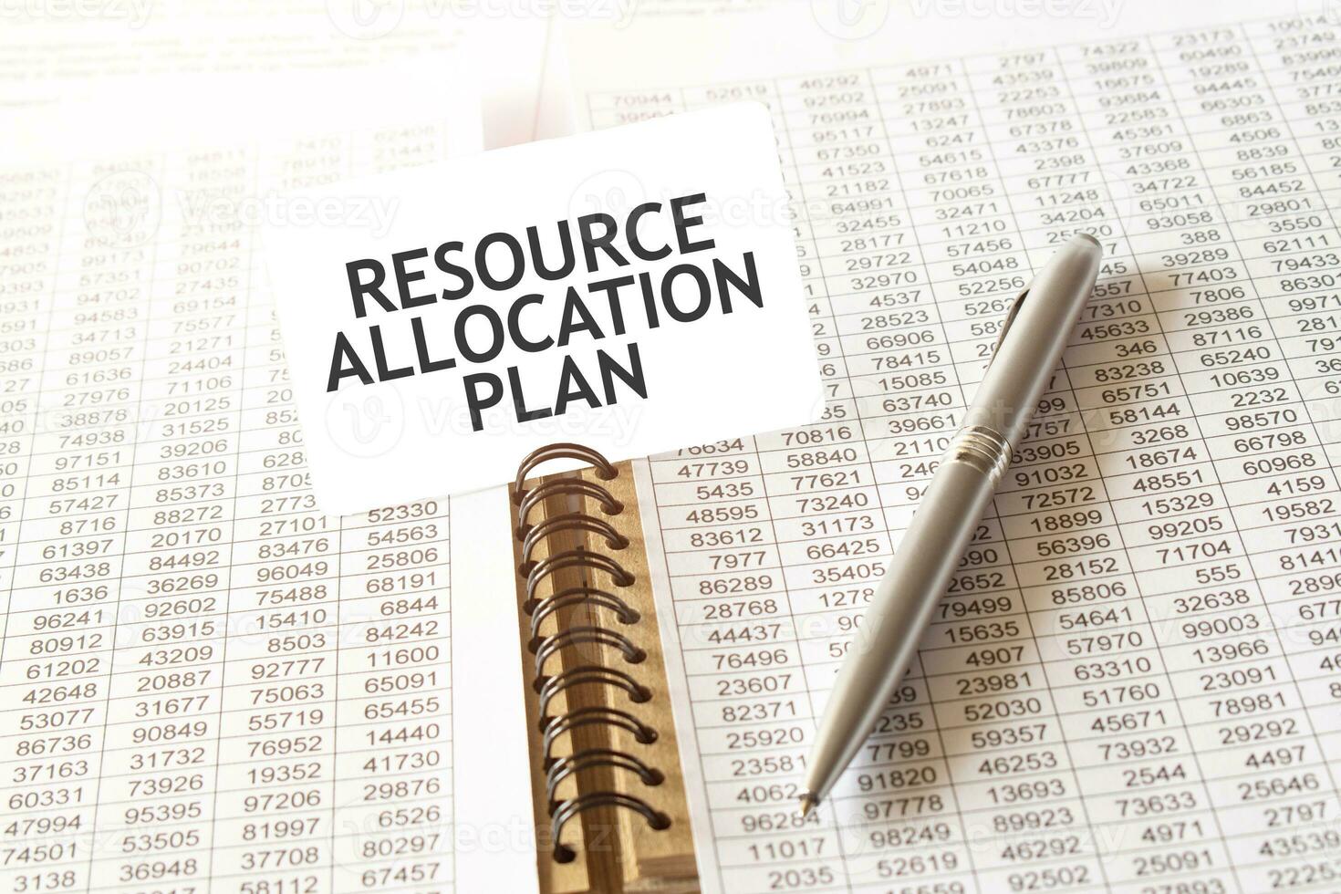 Text RESOURCE ALLOCATION PLAN on paper card, pen, financial documentation on table photo