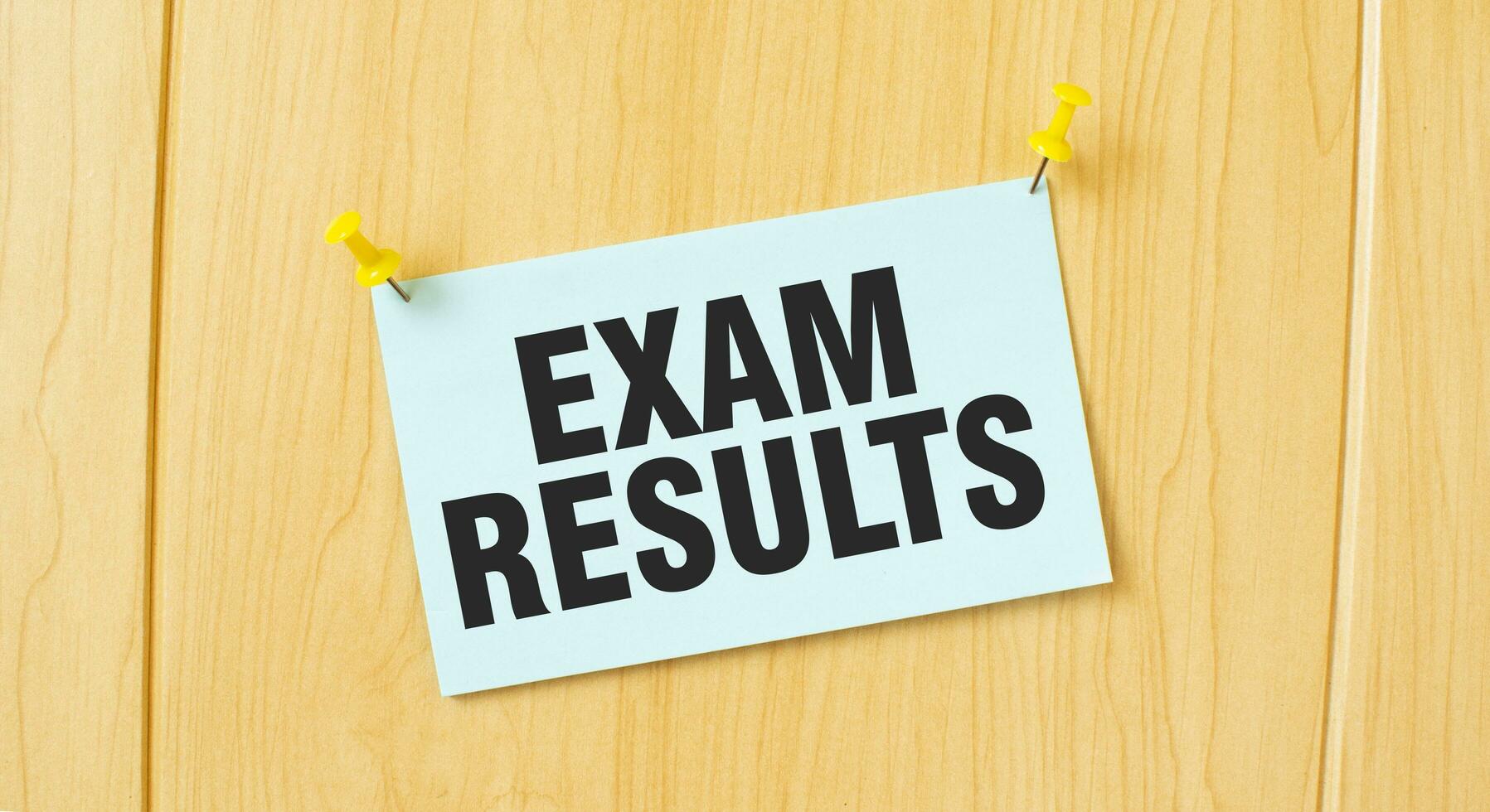EXAM RESULTS sign written on sticky note pinned on wooden wall photo