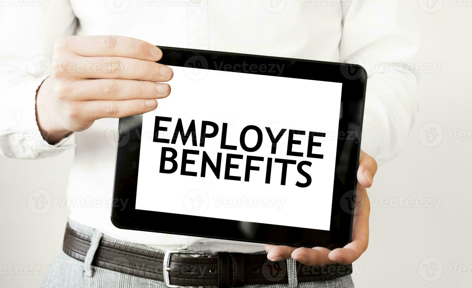 Text EMPLOYEE BENEFITS on tablet display in businessman hands on the white background. Business concept photo