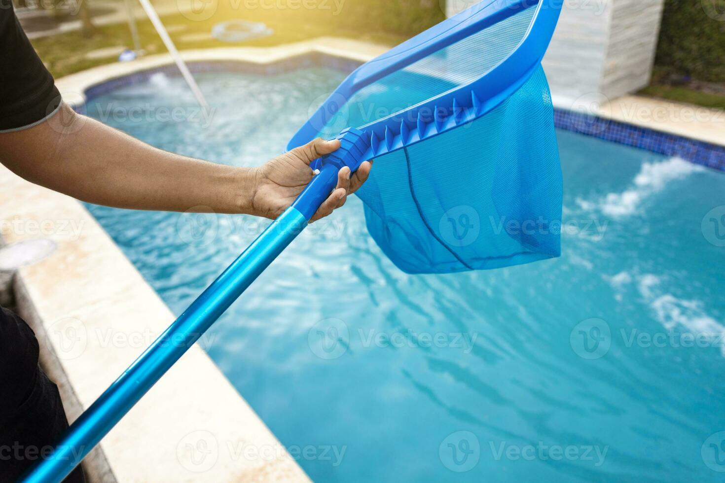 persona con desnatadora limpieza piscina, manos participación un desnatadora con azul piscina en el antecedentes. hombre limpieza el piscina con el desnatadora, un hombre limpieza piscina con hoja desnatadora foto