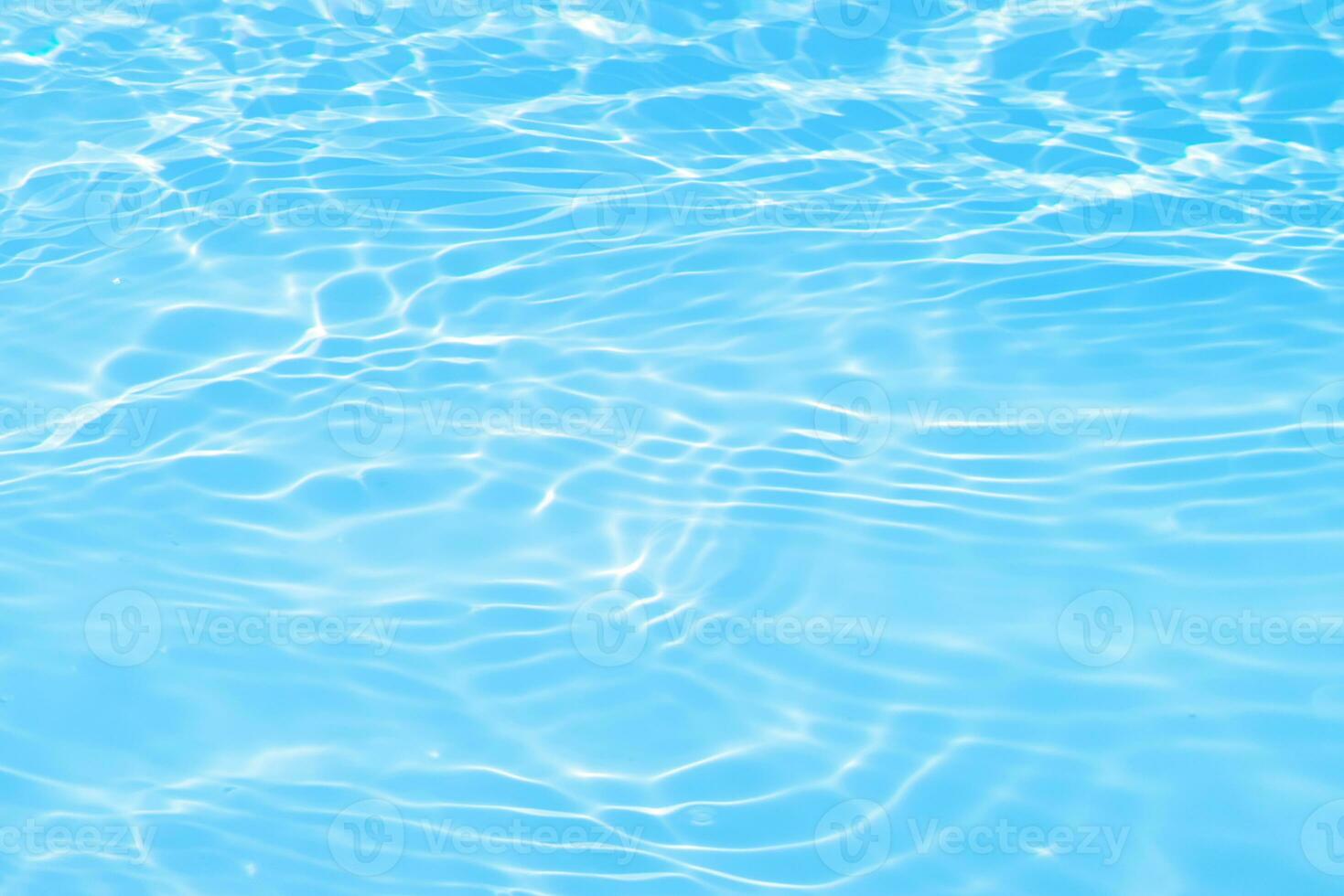 Blue water with ripples on the surface. Defocus blurred transparent blue colored clear calm water surface texture with splashes and bubbles. Water waves with shining pattern texture background. photo