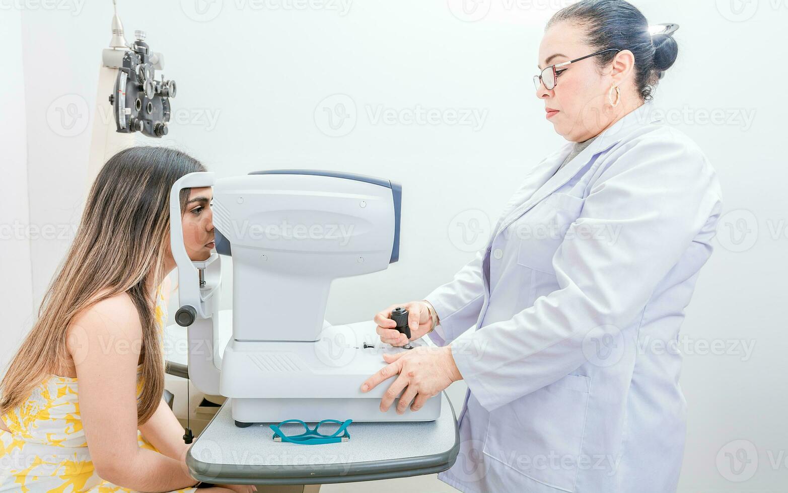 Optometrist checking the eyesight of a patient with an autorefractor. Oculist doing eye exam to female patient photo
