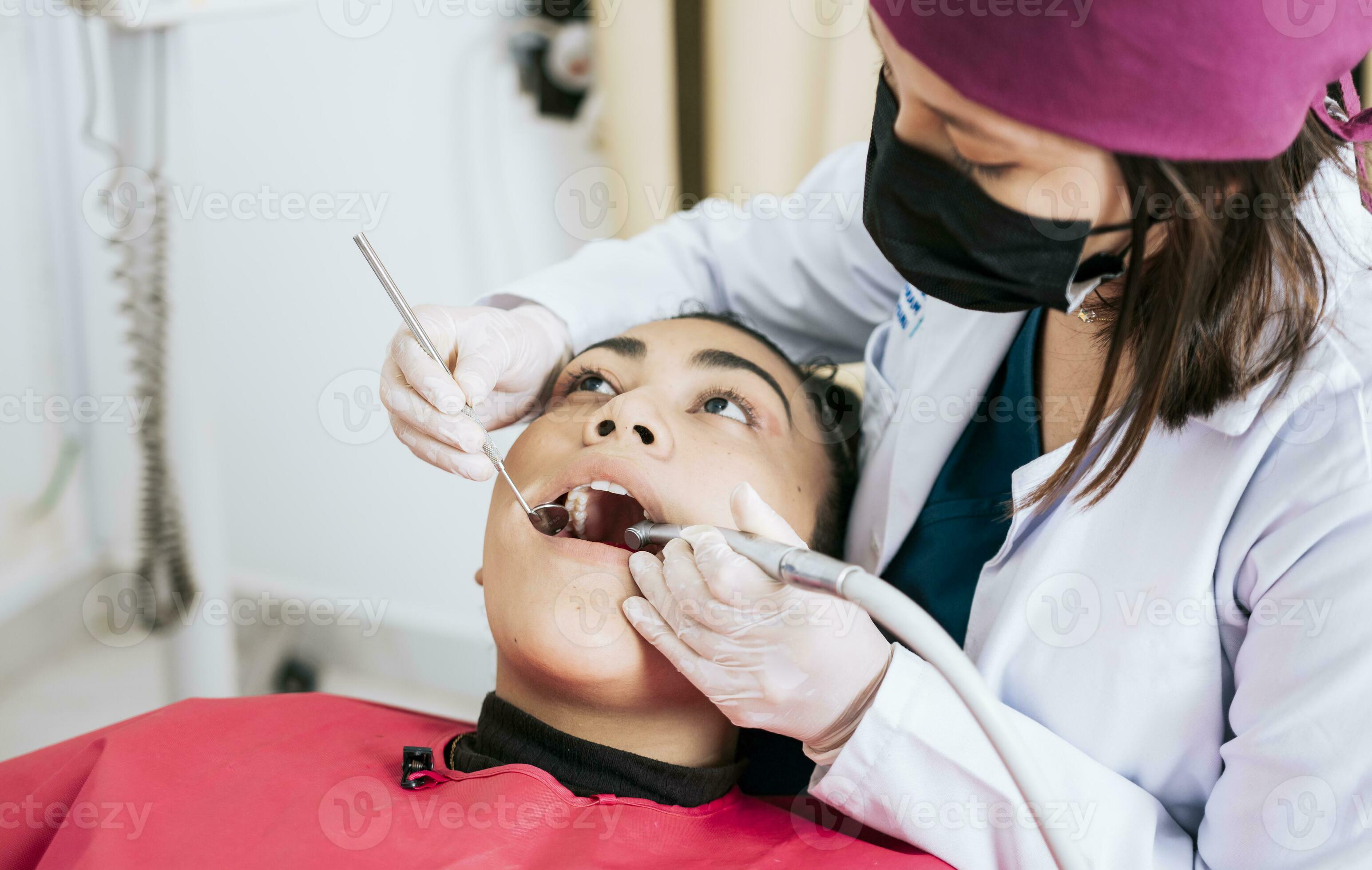 Female dentist cleaning and examining a female patient mouth. Dental