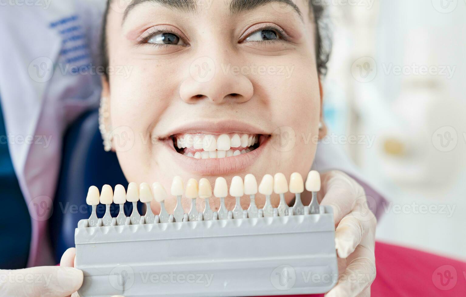 Dentist holding a set of implants with various shades of tone. Patient selecting the shade of dental implant. Implant tooth shade selection, Dentist showing dental prosthesis shades to patient photo