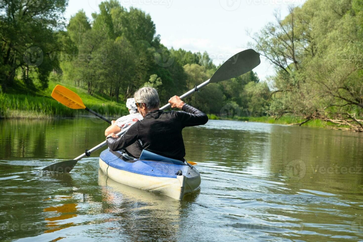 Family kayak trip for seigneur and senora. An elderly married couple rowing a boat on the river, a water hike, a summer adventure. Age-related sports, mental youth and health, tourism, active old age photo