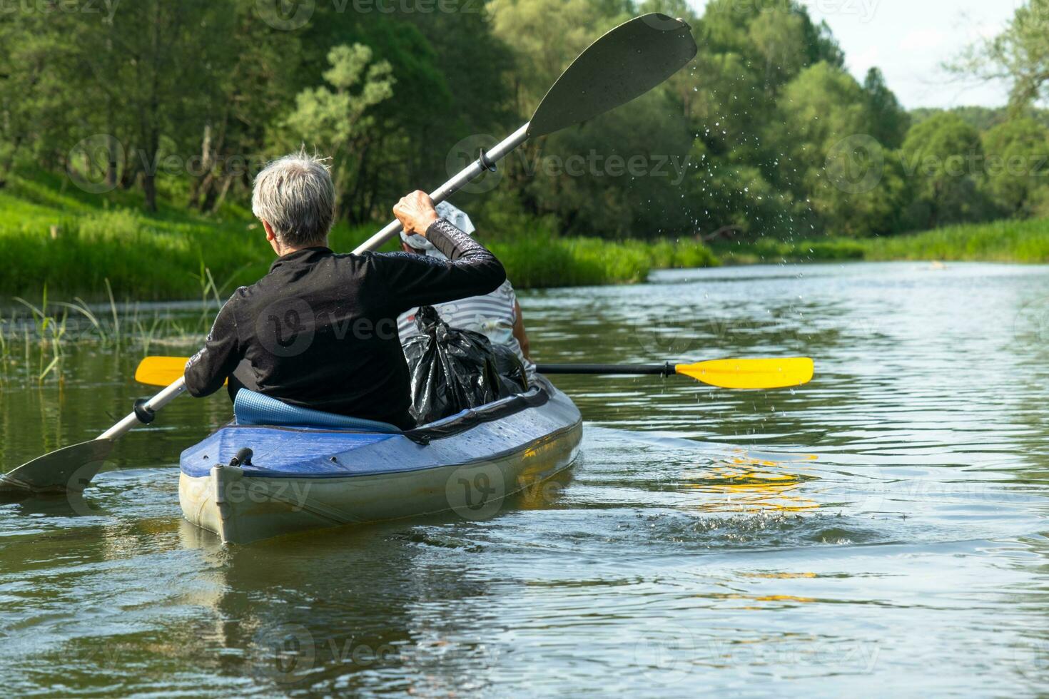 Family kayak trip for seigneur and senora. An elderly married couple rowing a boat on the river, a water hike, a summer adventure. Age-related sports, mental youth and health, tourism, active old age photo