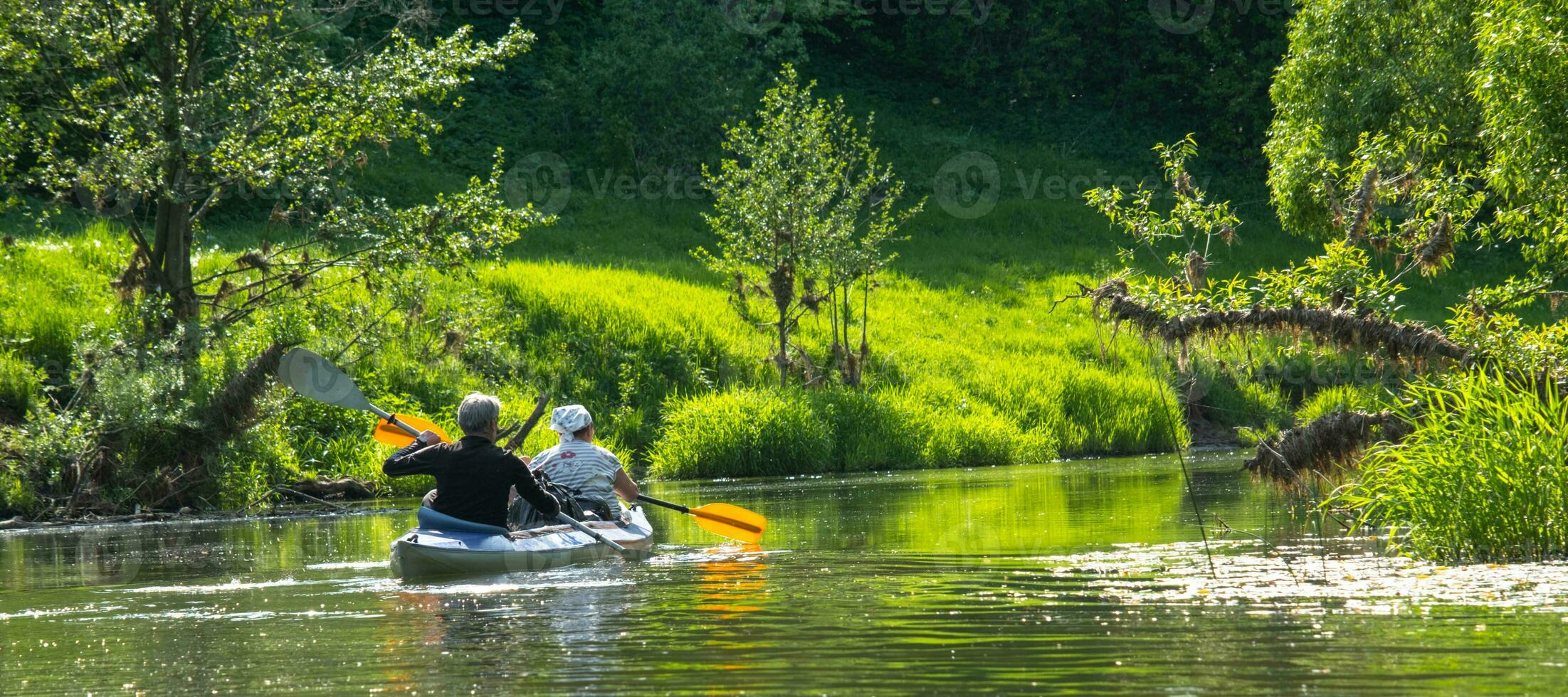 Family kayak trip for seigneur and senora. An elderly married couple rowing a boat on the river, a water hike, a summer adventure. Age-related sports, mental youth and health, tourism, active old age photo