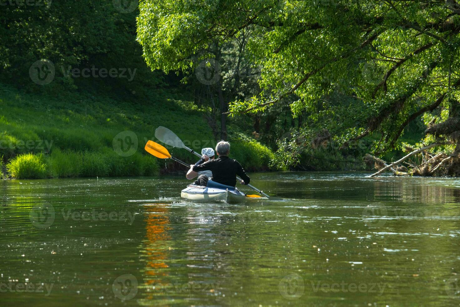 Family kayak trip for seigneur and senora. An elderly married couple rowing a boat on the river, a water hike, a summer adventure. Age-related sports, mental youth and health, tourism, active old age photo