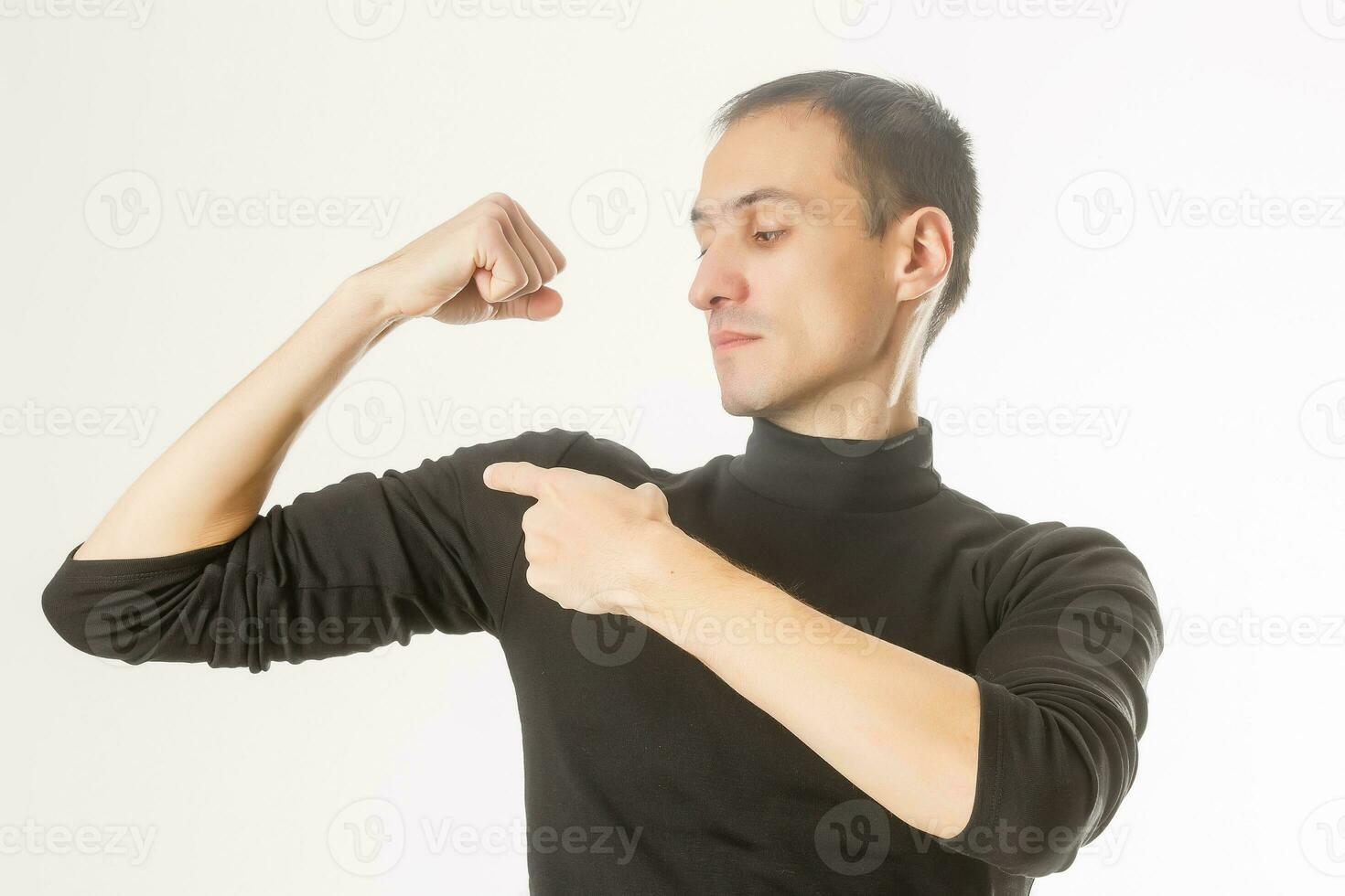 Portrait of young handsome dark-haired man , holding his arm up to show how strong he, isolate white background photo