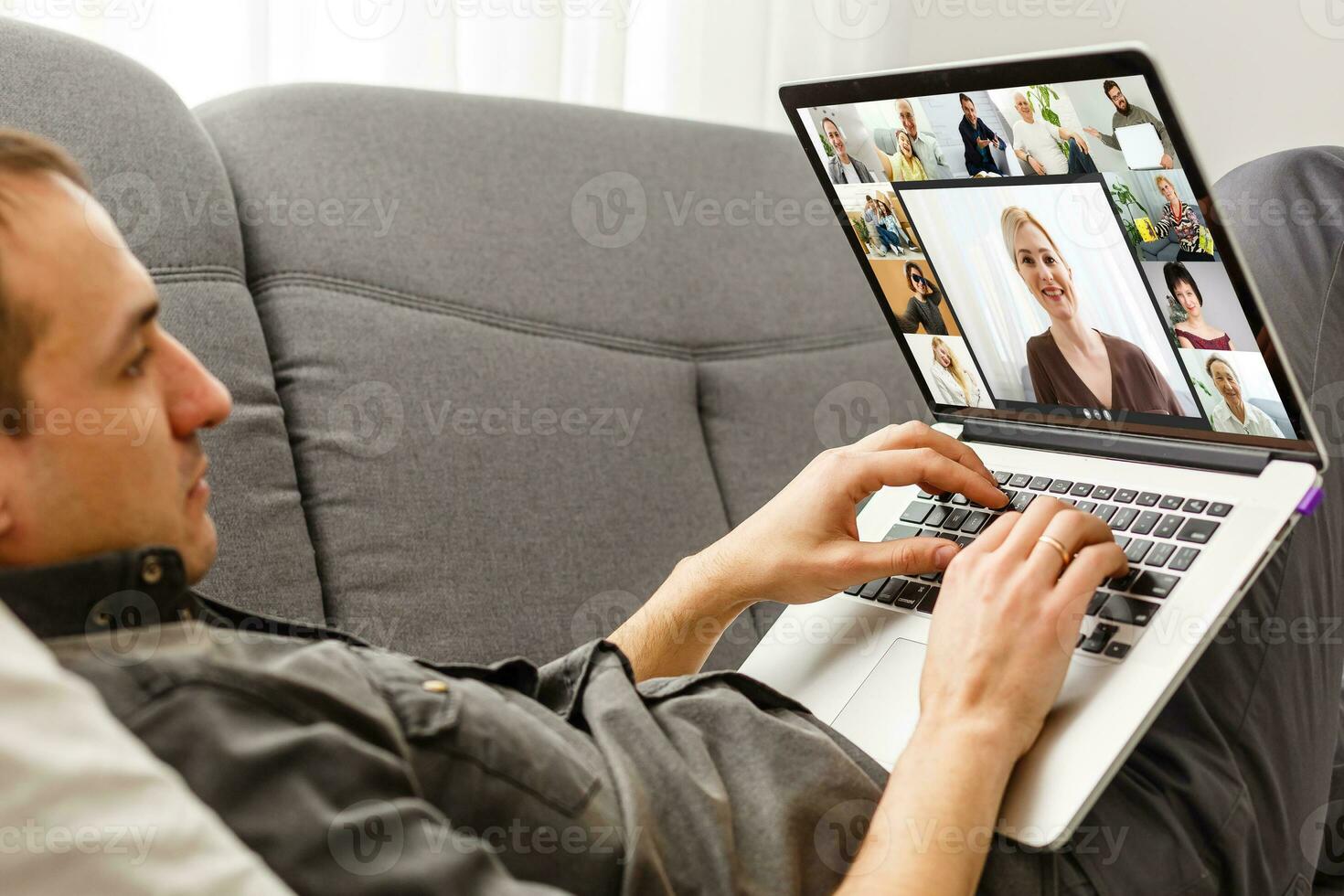 Back view of young man using headset and laptop and having videoconference at home photo