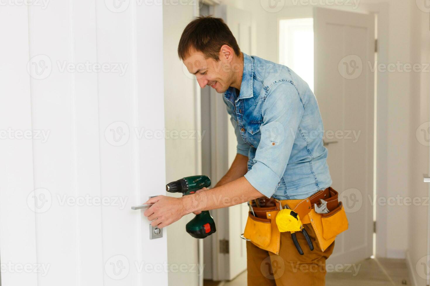 young repairman checking new door lock photo