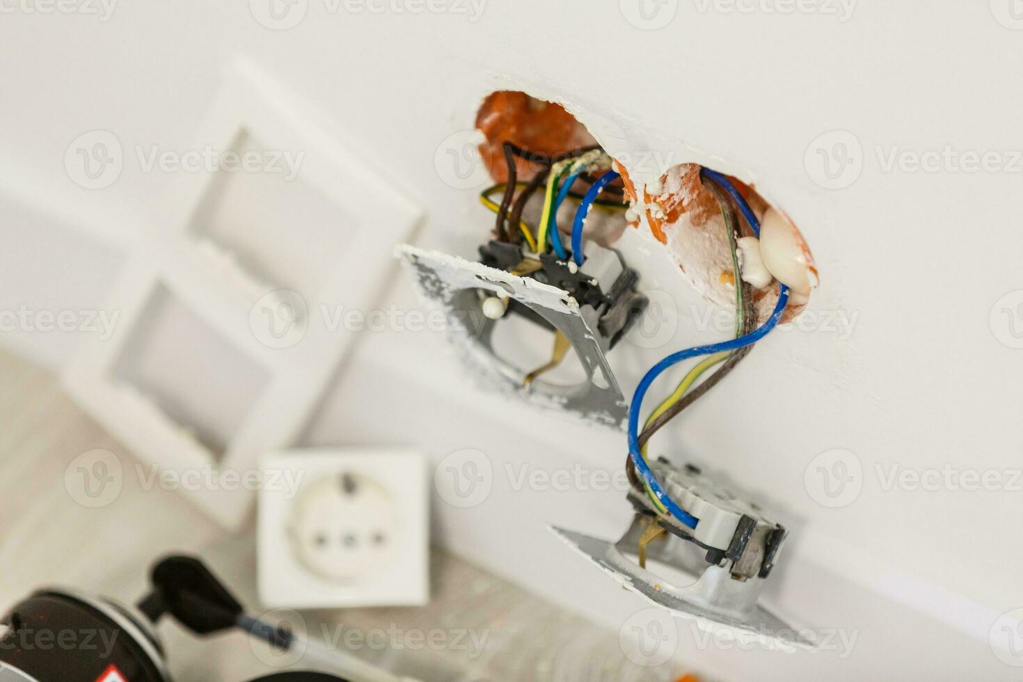 Unfinished electrical mains outlet socket with electrical wires and connector installed in plasterboard drywall for gypsum walls in apartment is under construction and reconstruction. photo