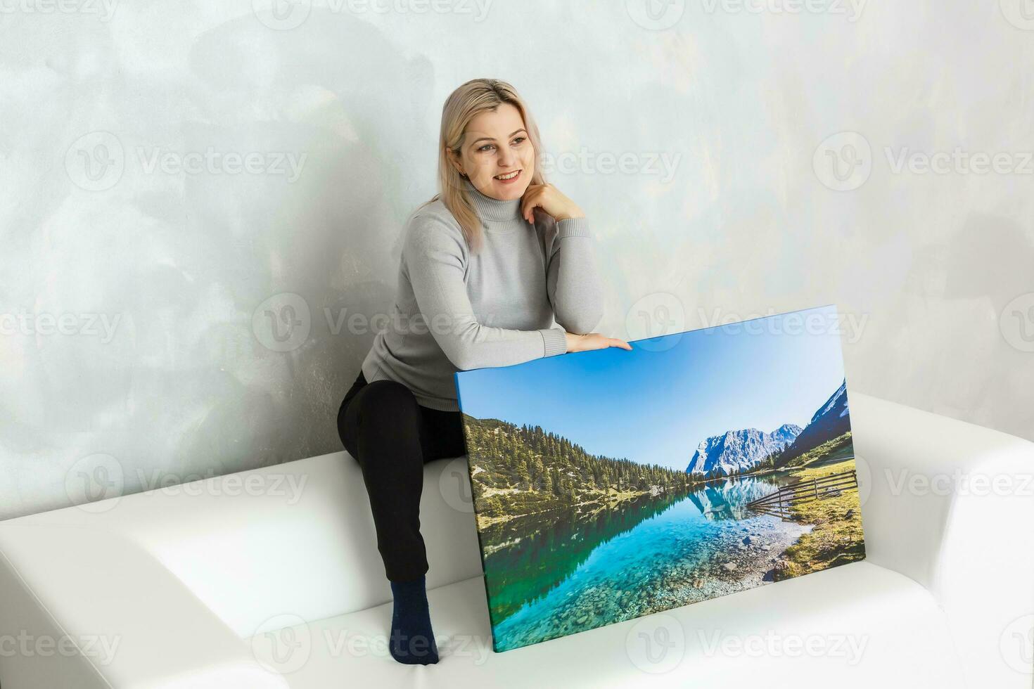 Young girl holds photo canvas at home on the couch